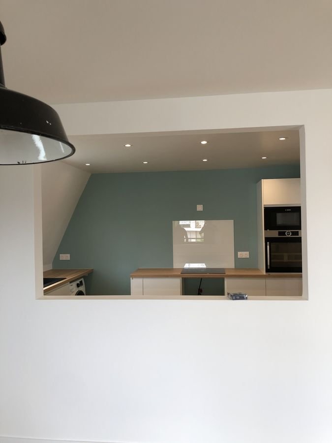 Cuisine ouverte sur le séjour avec mur bleu-vert