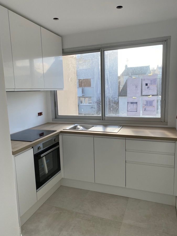 Cuisine blanche avec plan de travail en bois et fenêtre