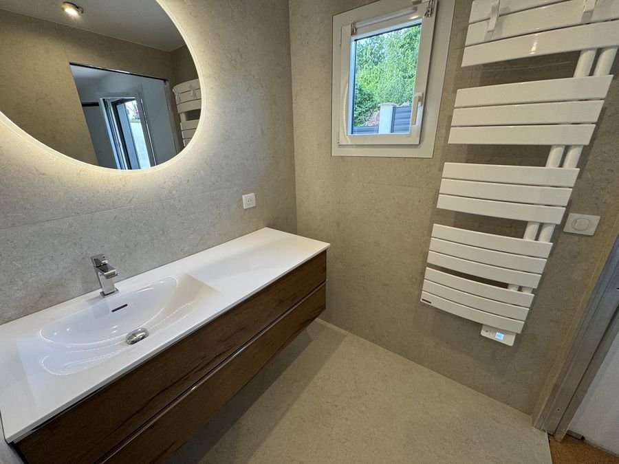 Salle de bains avec vasque, miroir rond et radiateur sèche-serviettes